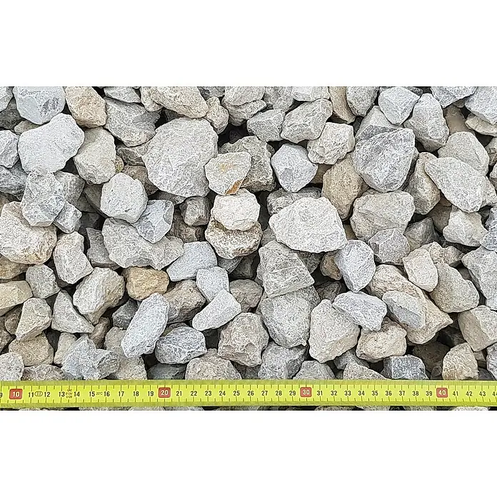 BHS Mallorca Big Bag de grava 3 -  - Un montón de piedras trituradas de color claro adecuadas para fines de construcción, con una cinta métrica amarilla como referencia de tamaño.