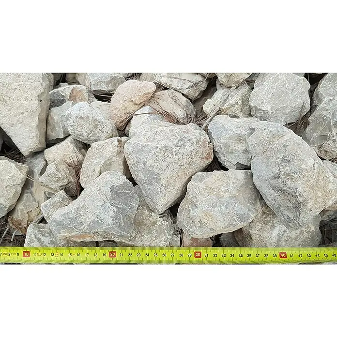 BHS Mallorca Big Bag de machaca - Grano: 40 mm - 125 mm, 900 kg, Gris - Primer plano de rocas de piedra caliza gris de varios tamaños, medidas con una cinta métrica amarilla.