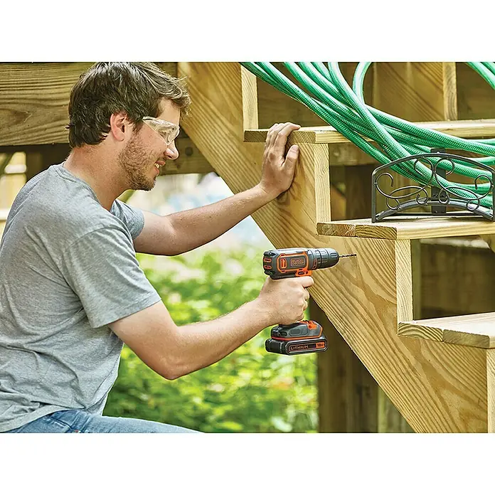 Black+Decker Akku-Bohrschrauber BDCDC18K-QW18 V, 1 Akku, 30 Nm - Ein Mann bohrt mit einem Akku-Bohrschrauber von Black+Decker in eine Holztreppe, während er Schutzbrille trägt.
