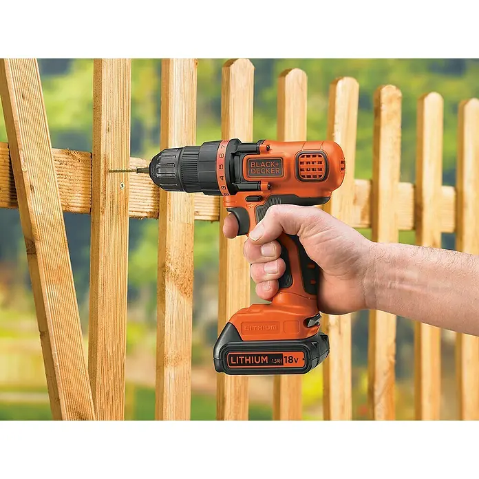 Black+Decker Akku-Bohrschrauber BDCDD18N-XJ - 18 V, Ohne Akku - Ein Black+Decker Akku-Bohrschrauber im Einsatz, um ein Holzbrett an einem Zaun zu befestigen. Der Schrauber ist orange und schwarz und hat einen Lithium-Ionen-Akku.