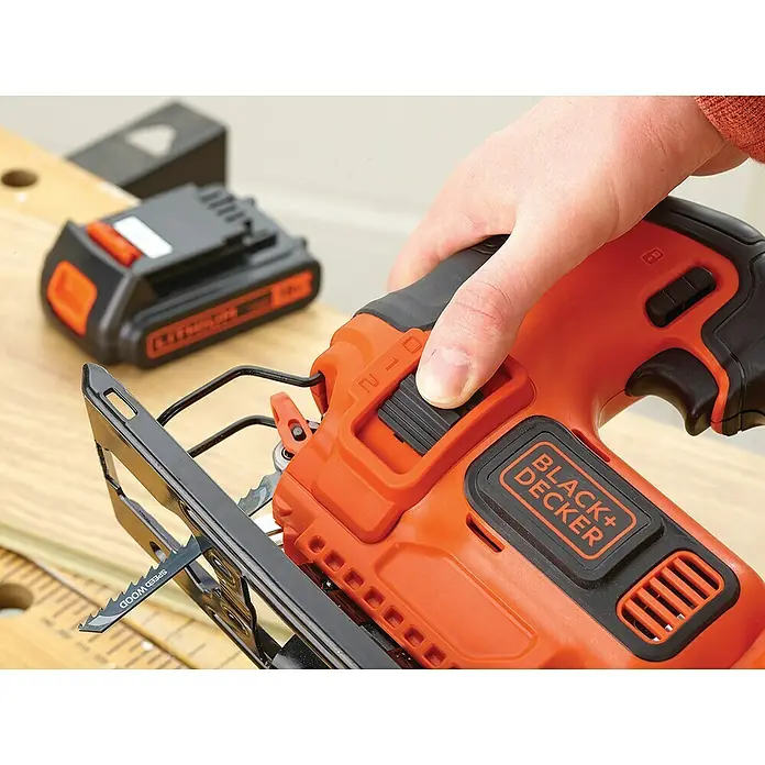 Black+Decker Pendelhubstichsäge BDCJS18-QW18 V, 1 Akku, 2 Ah, 0 /min - 2.500 /min - Eine Nahaufnahme einer orangefarbenen Black+Decker Stichsäge mit eingelegtem Sägeblatt, die von einer Hand bedient wird.