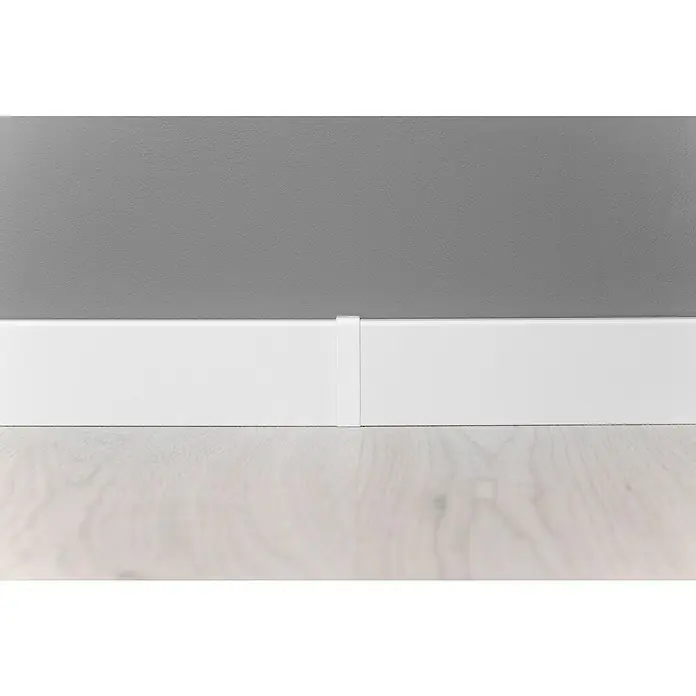 Übergangskappe Modern 58 - Weiß, 2 Stk. - Detailaufnahme von weißen Fußleisten, die einen sauberen Übergang zwischen grauer Wand und hellem Holzboden schaffen und eine moderne Ästhetik betonen.