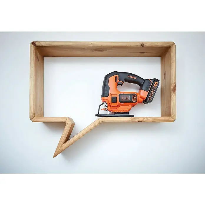 Black+Decker Pendelhubstichsäge BDCJS18-QW18 V, 1 Akku, 2 Ah, 0 /min - 2.500 /min - Stichsäge von BLACK+DECKER auf einem hölzernen, sprechblasen-förmigen Regal. Das Werkzeug ist orange mit schwarzen Akzenten.
