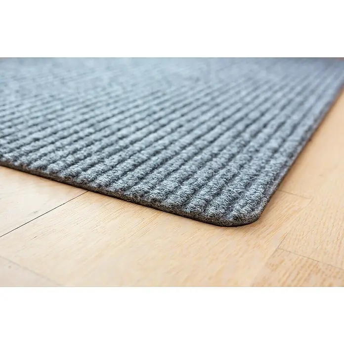 Astra Fußmatte Rib Line Sprint - 50 x 80 cm, Hellgrau, 100 % Polypropylen - Nahaufnahme einer grauen Fußmatte mit gerippter Textur, die auf einem hellen Holzboden liegt. Die Matte ist robust und ideal für den Eingangsbereich.