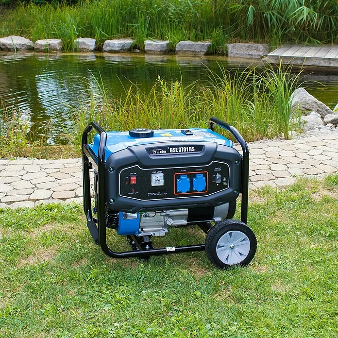 Güde Stromerzeuger GSE 3701 RS - 2,8 kW, Tankvolumen: 15 l, Verbrauch: 1,25 l/h - Das Bild zeigt einen blauen und schwarzen Güde GSE 3701 RS Stromgenerator im Freien vor einem Teich mit üppiger Vegetation.