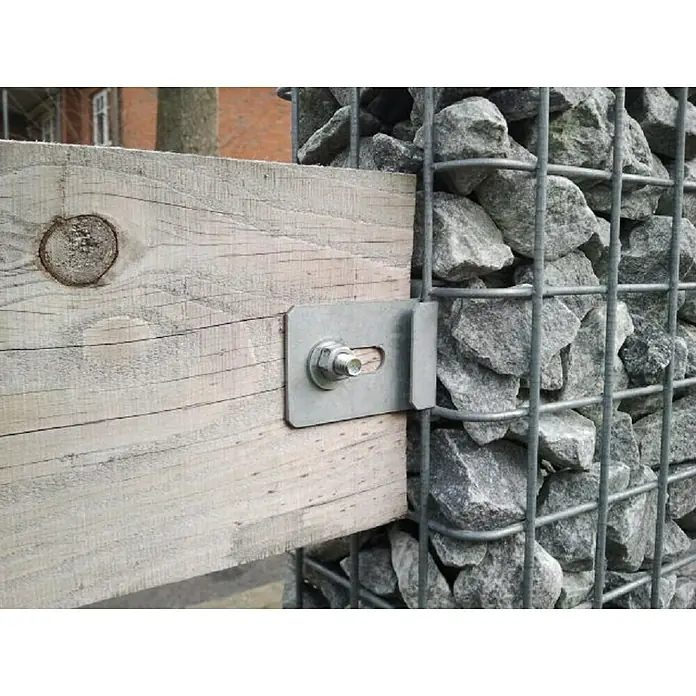 Gabiona ZaunhalterungPassend für: Gabionen mit einer Maschenweite von 5 x 5 cm - Nahaufnahme eines Holzpfostens, der mit einer Metallhalterung an einem Gabionenzaun befestigt ist. Die Halterung fixiert den Pfosten sicher am Steinkorb.