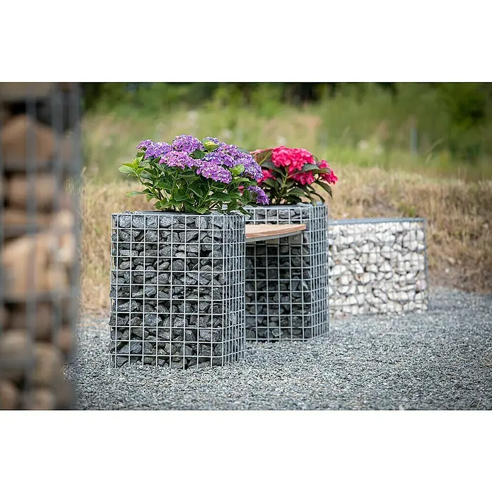 Gabiona Gabione Blumensäule42 x 42 x 82 cm, Metall, Maschenbreite: 50 mm, Maschenhöhe: 50 mm - Gabionen-Blumenkästen und eine Bank im Garten. Die Blumenkästen sind mit lila und pinkfarbenen Hortensien bepflanzt und die Bank bietet eine Sitzgelegenheit.