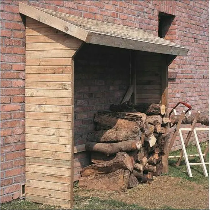 Cerland Leñero Memphis - Madera, Natural - Leñera cubierta de madera con leña apilada contra una pared de ladrillo, con una sierra y un caballete al lado.
