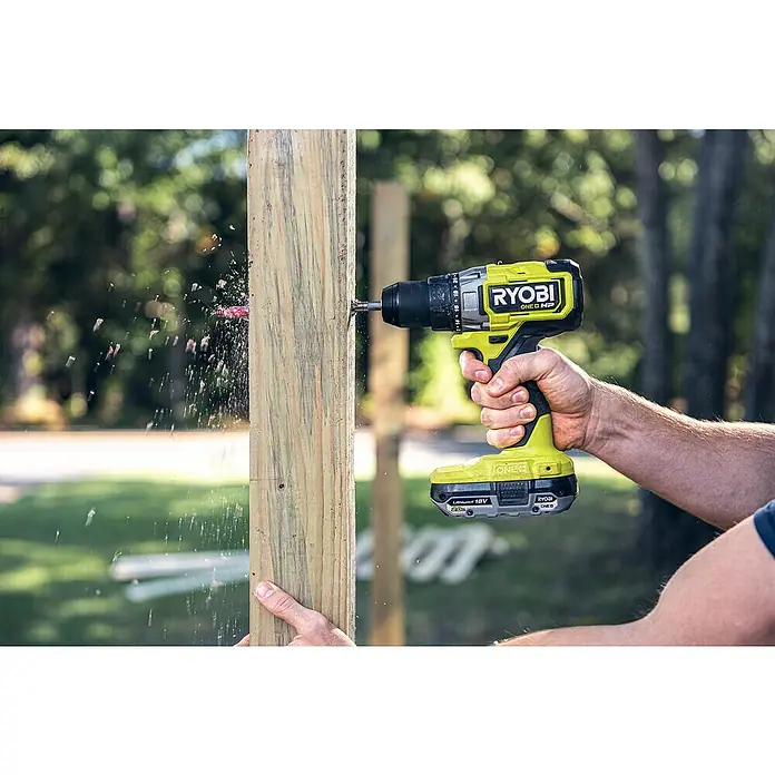 Ryobi ONE+HP Taladro atornillador de batería RDD18X - 18 V, Sin batería, 95 Nm - Un taladro inalámbrico amarillo Ryobi ONE+ HP perfora un agujero en un poste de madera, con virutas de madera volando. ¡Perfecto para cualquier aficionado al bricolaje!