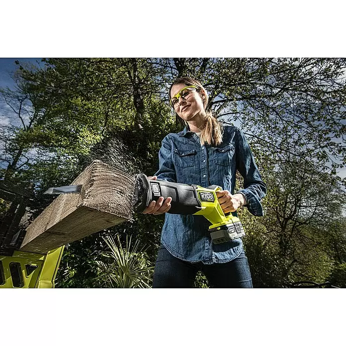 Ryobi ONE+HP Akku-Säbelsäge RRS18X-0 - 18 V, Hublänge: 32 mm, Ohne Akku - Frau sägt mit einer gelb-schwarzen Ryobi Säbelsäge ein Holzbrett, Sägespäne fliegen.