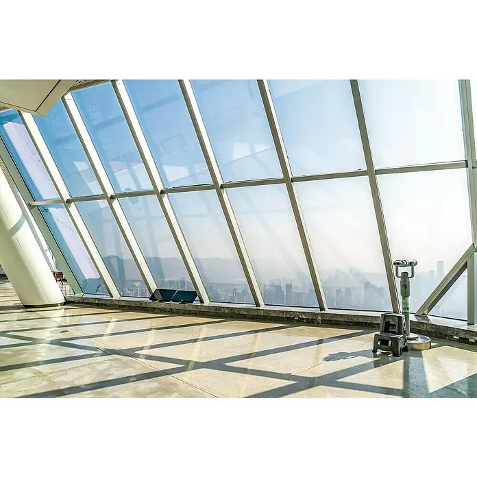 Protección de vinilo Transparente - Ancho: 92 cm, Transparente - Vista a través de una ventana panorámica con binoculares hacia un paisaje urbano borroso. La luz y las sombras crean patrones interesantes en el suelo.
