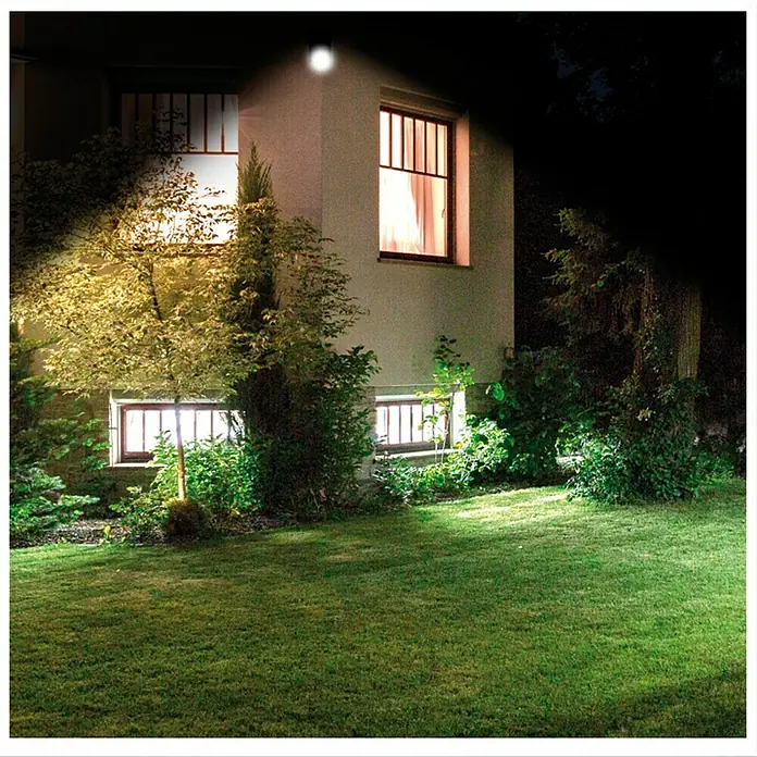 Foco solar Handy Brite - Sensor de luz - Toma exterior de una casa de noche con una luz exterior brillante que ilumina el jardín.