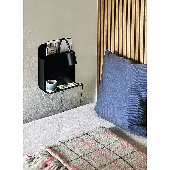 Nordlux Aplique de pared Roomi - 35 W, L x An x Al: 16,5 x 24,8 x 28,2 cm, Negro, GU10 - Estante de pared con lámpara, taza y teléfono sobre una cama con manta a cuadros. El estante es negro y ofrece almacenamiento práctico.