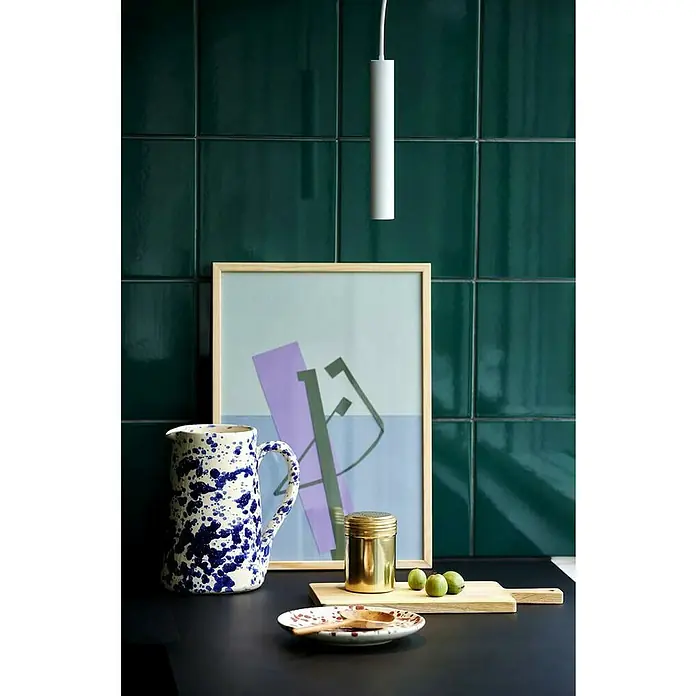 Nordlux Omari Lámpara colgante LED redonda - 3,3 W, Ø x Al: 3 x 20 cm, Blanco - Naturaleza muerta con jarra de cerámica salpicada de azul, recipiente dorado e impresión artística abstracta sobre azulejos verde esmeralda.