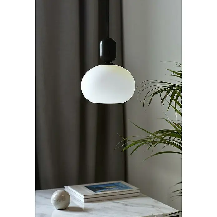 Nordlux Notti Lámpara colgante redonda - 40 W, Ø x Al: 20 x 23,8 cm, Negro, E27 - Primer plano de una lámpara colgante moderna con una esfera de vidrio blanco mate y un dosel negro, que cuelga sobre una mesa.