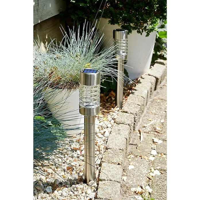 Luxform Solar-Erdspieß Torino - L x B x H: 7,5 x 7,5 x 58 cm, Silber, 8 lm - Nahaufnahme von zwei silbernen Solarleuchten im Garten, die eine stimmungsvolle Atmosphäre schaffen und gleichzeitig energiesparend sind.
