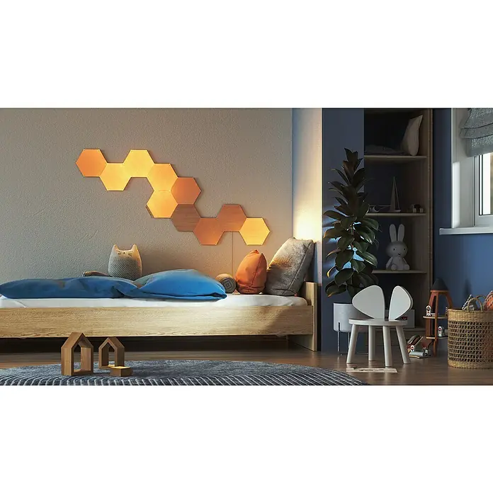Nanoleaf Erweiterungskit Elements Hexagons 3 Panels - 42 W, Holzoptik, Mehrfarbig, Hexagons, Smart Home-fähig: Ja - Ein Kinderzimmer mit einem hölzernen Bett, beleuchteten sechseckigen Wandpaneelen und einem Bücherregal mit Spielzeug und einer Pflanze.