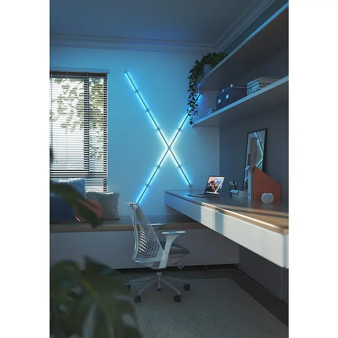 Nanoleaf Erweiterungskit Lines 60 Degrees 3 Lines - 3 Stk., Weiß, RGBW - Ein moderner Arbeitsbereich mit einem minimalistischen Schreibtisch und einer auffälligen, kreuzförmigen LED-Wandleuchte.