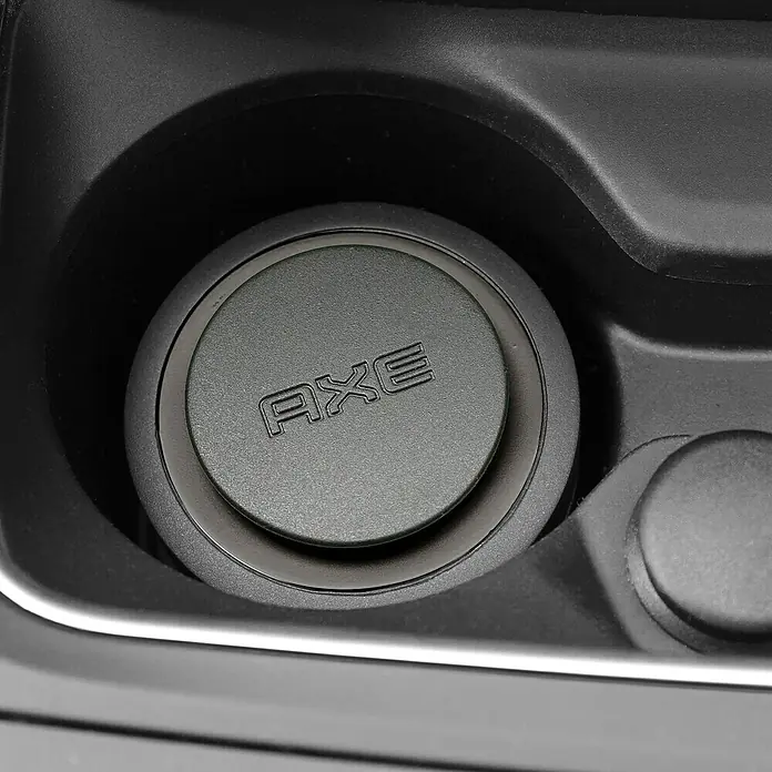 Axe Ambientador de coche Gel - Black - Primer plano de una tapa negra de la marca AXE en un portavasos, que muestra claramente el logotipo de la marca. Diseño compacto y elegante.