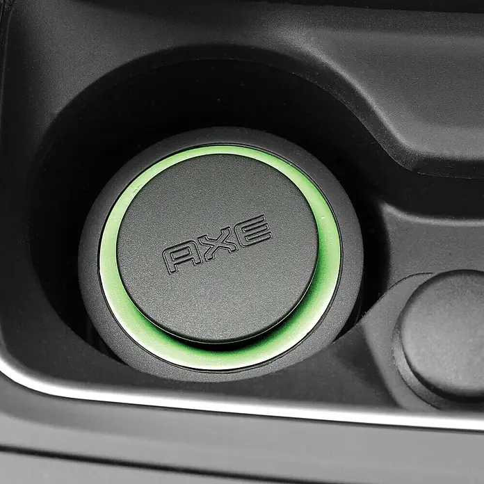 Axe Ambientador de coche Gel - Africa - Primer plano de una tapa negra de AXE con borde verde en un portavasos, resaltando el diseño del producto.