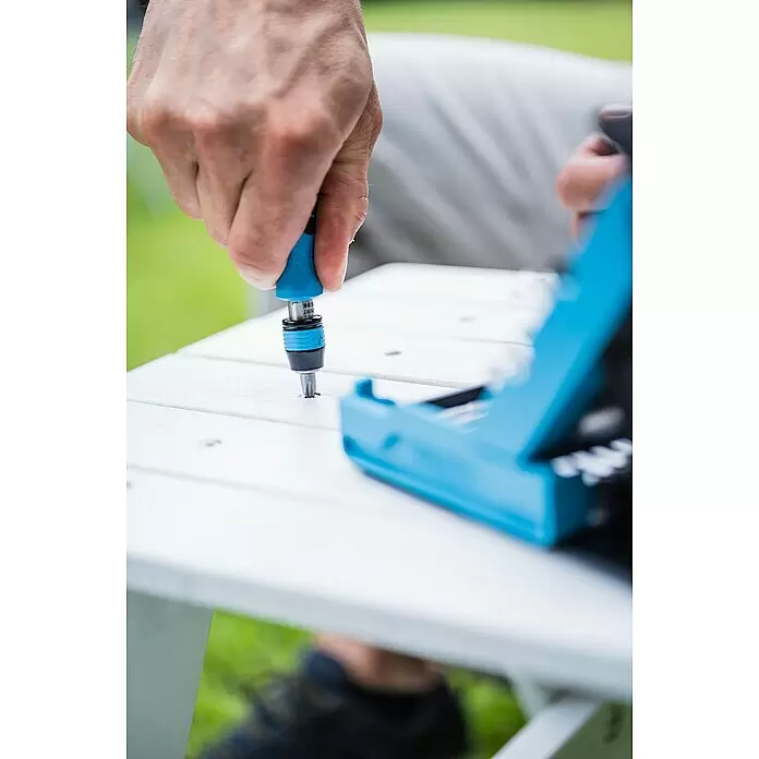 Hazet Set de puntas SmartCase - 69 ud. - Mano usando un destornillador azul y negro con punta Torx para fijar un tornillo en un panel blanco, con una caja de puntas azul cerca.