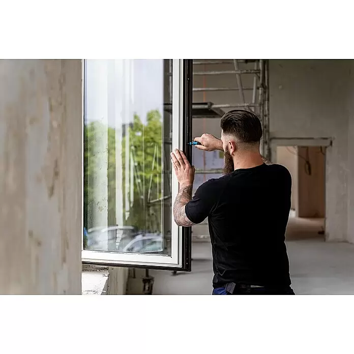 Hazet Set de puntas SmartCase - 69 ud. - Trabajador ajustando un marco de ventana blanco en un edificio en construcción.