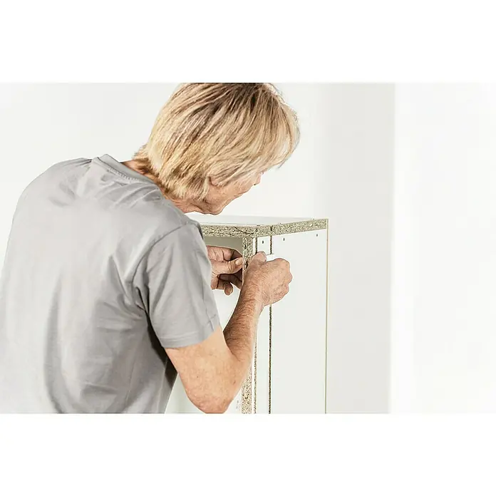 Knauf Wandnischen-Set L - 80 x 36,2 cm - Ein Mann montiert ein Möbelstück, wobei er Schrauben verwendet, um die Teile zu verbinden. Fokus liegt auf der Montage des Möbelstücks.