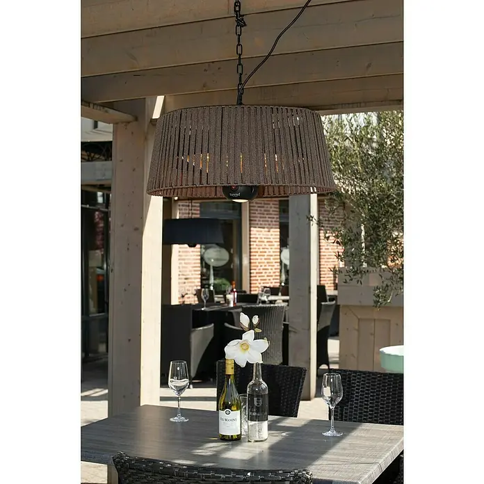 Sunred Halogen-Heizstrahler Corda hängend - Durchmesser: 60 cm, 1.800 W, Braun - Einrichtung für den Außenbereich mit Heizstrahler. Die Sunred-Terrassenheizung hängt über einem Tisch mit Weinflaschen und Gläsern.