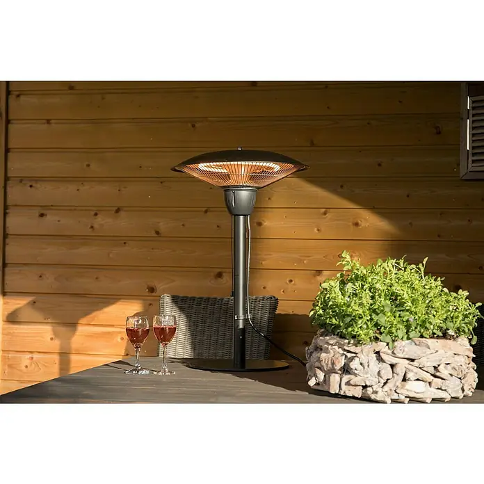 Sunred Halogen-Heizstrahler Barcelona - Ø x H: 44 x 66 cm, 1.500 W, Schwarz - Terrassenheizer auf einem Tisch mit Weingläsern & einem Steintopf voller Pflanzen vor einer Holzwand. Ideal für gemütliche Abende im Freien.