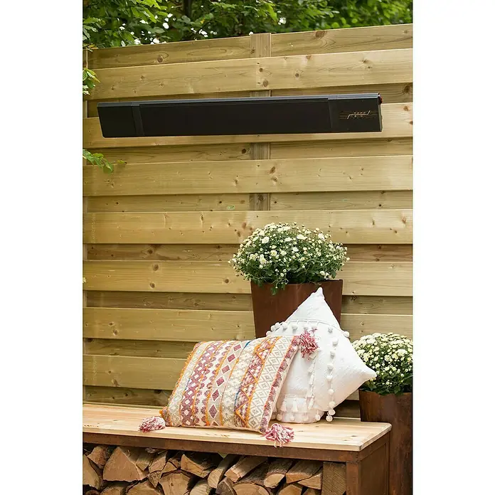 Sunred Heizstrahler Nero - 2.400 W, Schwarz, Breite: 116 cm - Eine schwarze Terrassenheizung hängt an einer Holzwand über einer Bank mit Kissen und Blumen. Sie spendet Wärme und Licht für gemütliche Stunden.