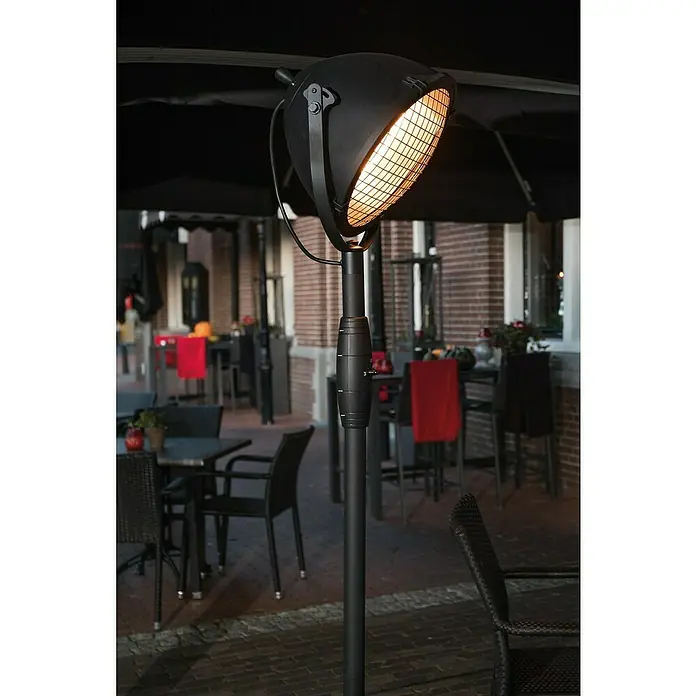 Sunred Halogen-Heizstrahler Indus - Höhe: 210 cm, 2.100 W, Schwarz - Eine Nahaufnahme eines schwarzen Heizstrahlers mit einem leuchtenden Heizkörper auf einer Terrasse, umgeben von Tischen und Stühlen.