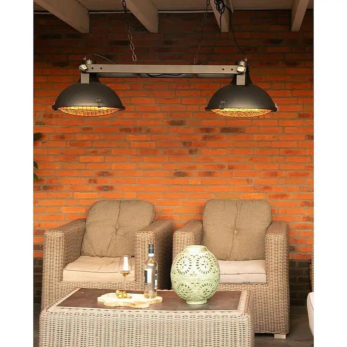 Sunred Halogen-Heizstrahler Indus - L x B: 132 x 42,5 cm, 3.000 W, Schwarz - Gemütliche Terrassenszene mit zwei Rattansesseln, einem Couchtisch mit Dekoration und einer Hängelampe, die warmes Licht spendet.