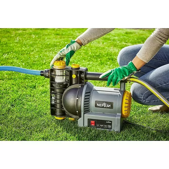 Neptun Gartenpumpe NGP-E 120 - 1.200 W, Max. Fördermenge: 4.600 l/h - Behandschuhte Hände justieren eine grau-gelbe Wasserpumpe mit transparentem Filter und angeschlossenen Schläuchen.