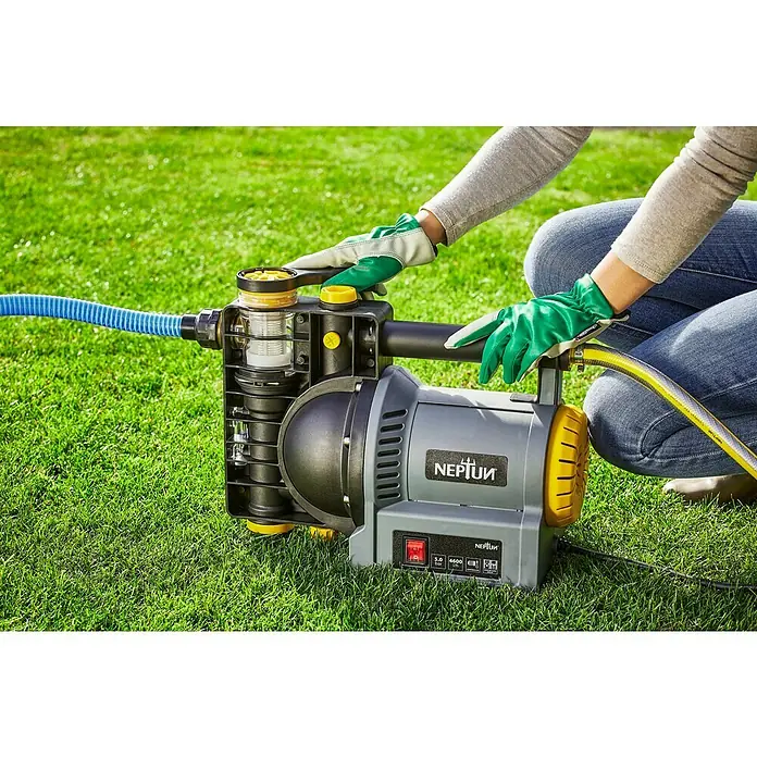 Neptun Gartenpumpe NGP-E 120 - 1.200 W, Max. Fördermenge: 4.600 l/h - Eine Nahaufnahme einer Person, die eine Neptun-Gartenpumpe mit blauen und gelben Schläuchen auf einem Rasen bedient.