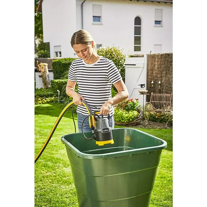 Neptun Bomba de achique sumergible para agua limpia NKP-E 22 - 220 W, Capacidad de bombeo máx.: 7.500 l/h - Una mujer baja una bomba sumergible Neptun en un recipiente verde lleno de agua.