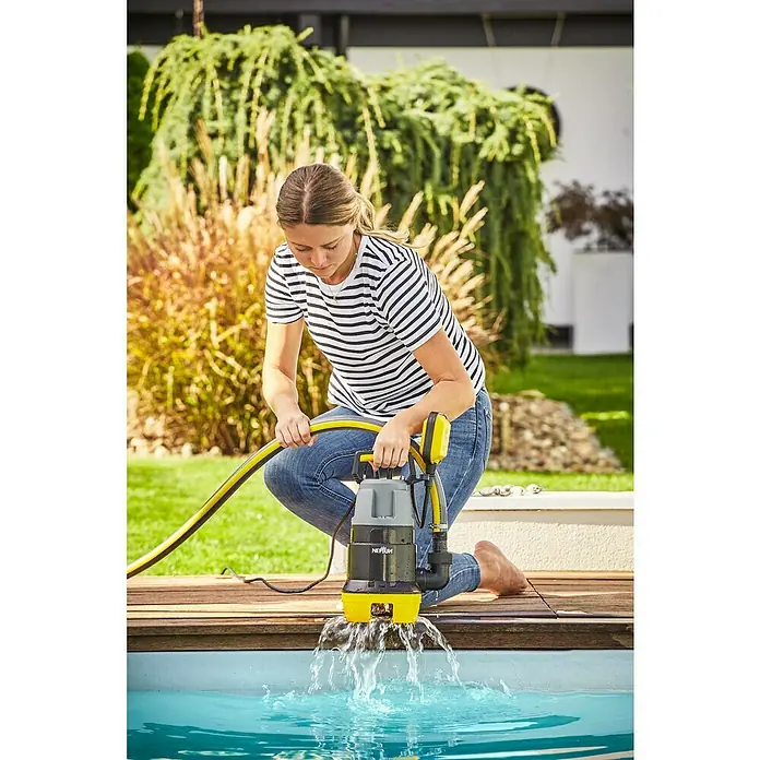 Neptun Bomba para aguas residuales NSP-E 75 - 750 W, Capacidad de bombeo máx.: 15.500 l/h, Profundidad de inmersión: 7 m - Una mujer está usando una bomba Neptun para bombear agua de una piscina. La bomba es amarilla y negra.
