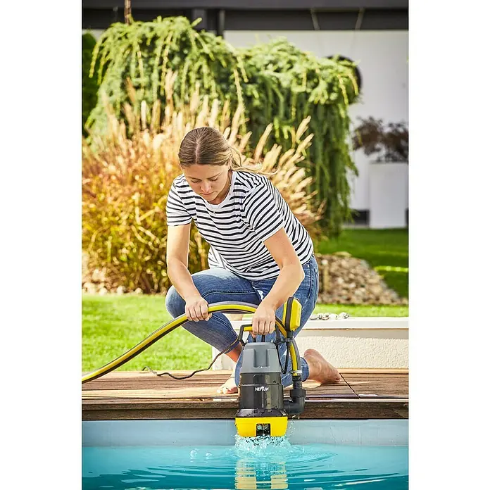Neptun Schmutzwasserpumpe NSP-E 75 - 750 W, Max. Fördermenge: 15.500 l/h, Eintauchtiefe: 7 m - Frau bedient eine gelbe und graue Neptun-Tauchpumpe, um das Wasser aus einem Pool abzupumpen.