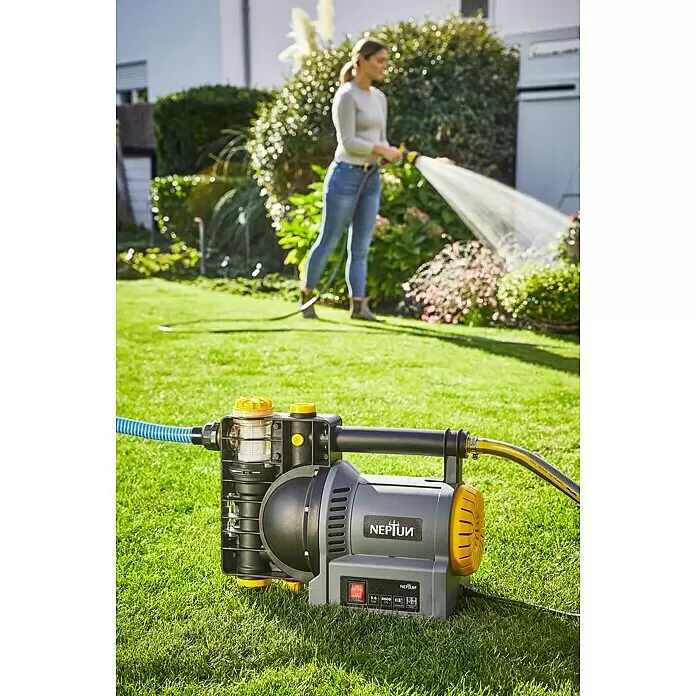 Neptun Gartenpumpe NGP-E 120 - 1.200 W, Max. Fördermenge: 4.600 l/h - Graue und gelbe Gartenpumpe mit Schläuchen auf Gras, eine Person bewässert Pflanzen im Hintergrund.