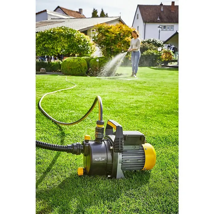 Neptun Bomba de agua para jardín NGP-E 68 - 680 W, Capacidad de bombeo máx.: 3.800 l/h, Altura de aspiración máx.: 8 m - Bomba de jardín Neptun en uso, una mujer riega el césped al fondo. Ideal para el riego del jardín.