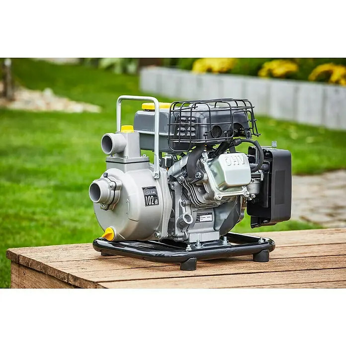 Neptun Benzinwasserpumpe NBP-E 16 - 1,6 kW, Max. Fördermenge: 14.000 l/h - Nahaufnahme einer grauen Wasserpumpe auf einem Holztisch vor einem Rasen. Die Pumpe hat einen schwarzen Rahmen und gelbe Akzente.