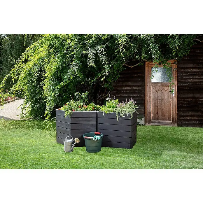 Garantia Hochbeet Ergo Vario 3 Wood Set - 175 x 110 x 75 cm, Kunststoff, Anthrazit/Braun - Ein erhöhter Pflanzkasten aus Holz, gefüllt mit Gemüse und Kräutern, neben einer Gießkanne und einem Eimer im Garten.