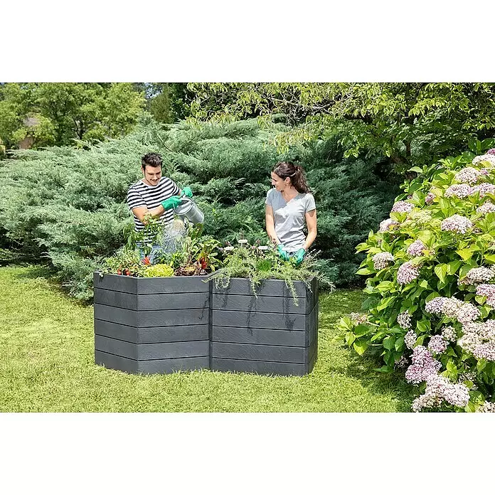 Garantia Hochbeet Ergo Vario 3 Stone Set - 175 x 110 x 75 cm, Kunststoff, Anthrazit - Dunkelgraue Hochbeete mit Pflanzen und Gemüse, von einem Paar im Garten bewässert.
