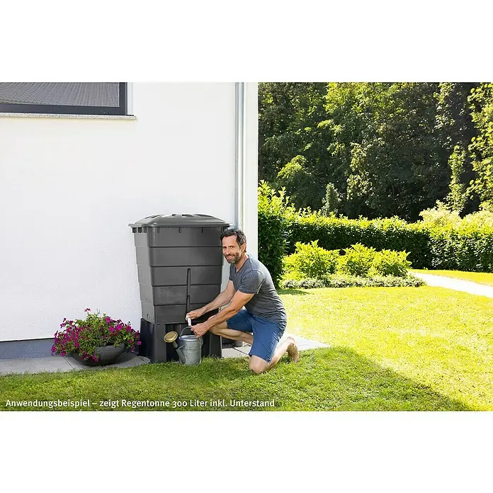 Garantia Basic Line Regentonne - 300 l, Graphite grey - Der Regenspeicher 300 Liter mit Unterstand in Anthrazit wird von einem Mann vorgeführt. Das Regenwasser kann mit einer Gießkanne entnommen werden.