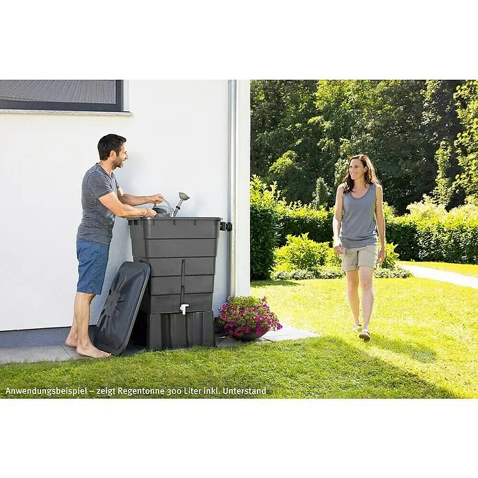 Garantia Basic Line Regentonne - 300 l, Graphite grey - Anwendungsbeispiel einer 300 Liter Regentonne inkl. Unterstand im Garten. Der Behälter ist dunkelgrau und eckig, mit Blumen geschmückt.