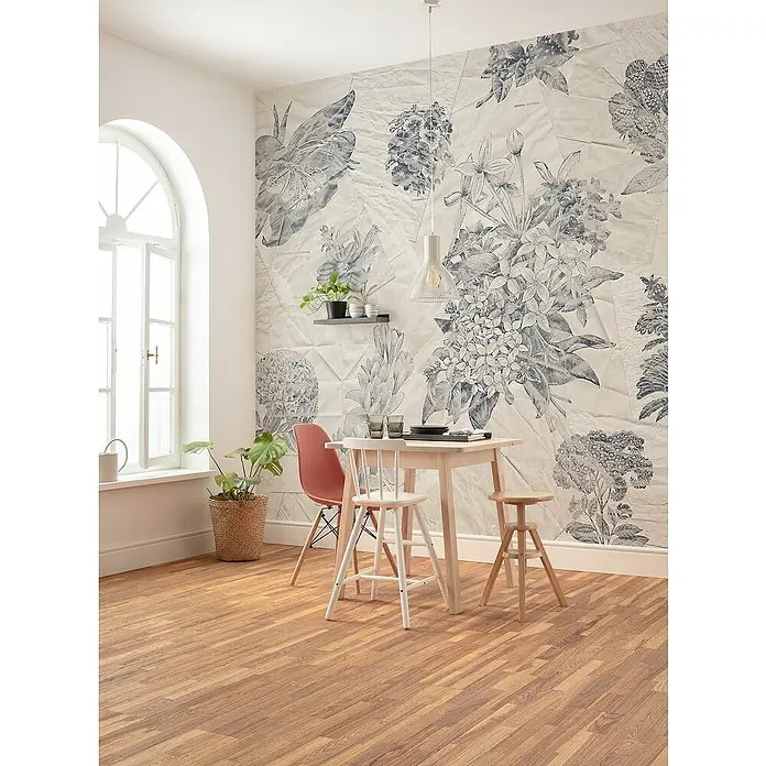 Komar Raw Fototapete Botanical Papers - B x H: 400 x 280 cm, Vlies - Ein Esszimmer mit einem Holztisch, Stühlen und einer floralen Tapete. Die natürliche Beleuchtung betont die Einrichtung.