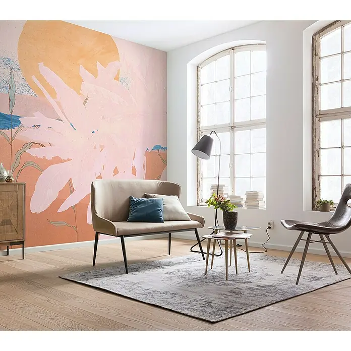 Komar Ink Fototapete Platanos Pink - 5 -tlg., B x H: 250 x 280 cm, Vlies - Einladendes Wohnzimmer mit einem stilvollen beigen Sofa, einem grauen Teppich und einem auffälligen floralen Wandbild.