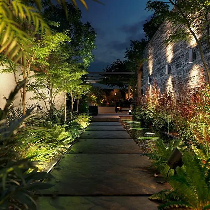 Philips Hue LED-Außenleuchte Amarant - Farbe Gehäuse: Schwarz, IP65, 20 W - Gartenlandschaft bei Nacht mit Beleuchtung.
