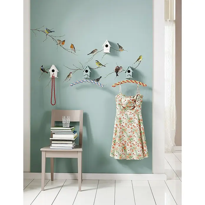 Komar Dekosticker Vogerl - 15 -tlg. - Schönes ärmelloses Sommerkleid mit Blumenmuster, das an einem verzierten Kleiderbügel an einer Wand mit Vogelmotiven hängt.
