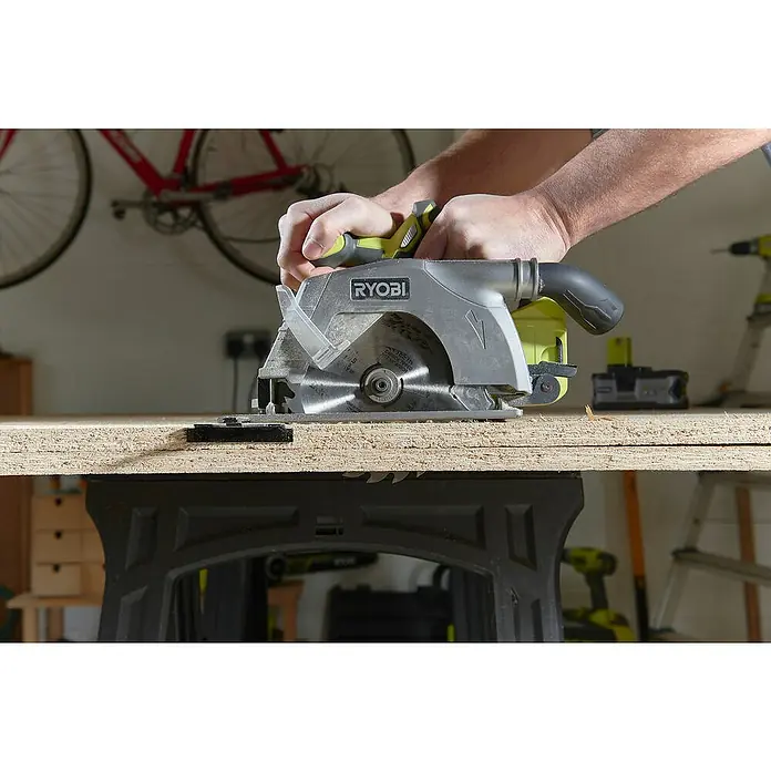 Ryobi ONE+ Maschinenpaket - Akku-Handkreissäge R18CS-0 + gratis Starter-Kit - Nahaufnahme einer Ryobi Kreissäge in Aktion, die ein Holzbrett durchtrennt, mit sichtbaren Sägeblättern und einer Hand, die das Werkzeug führt.