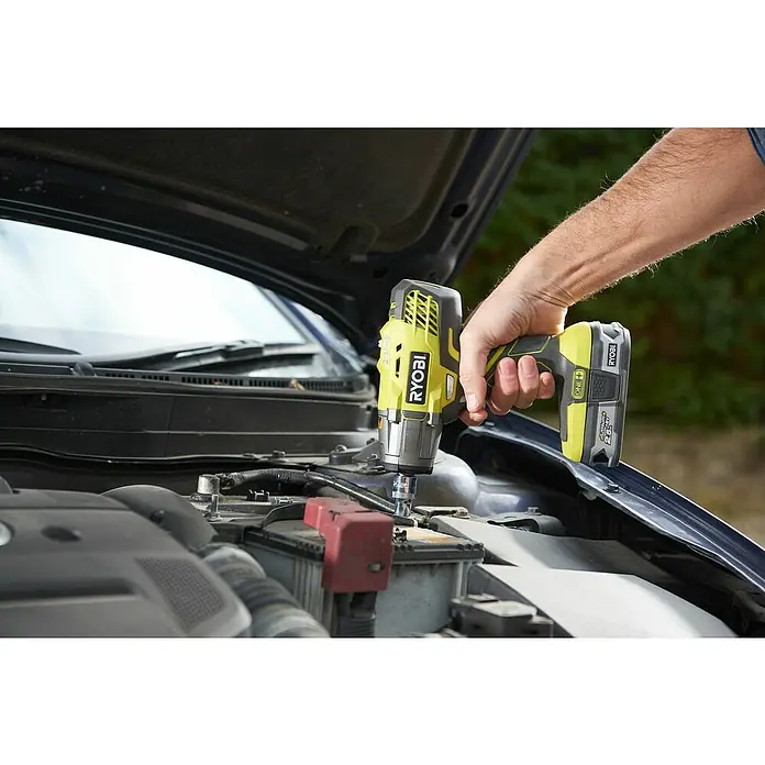 Ryobi ONE+ Akku-Schlagschrauber R18IW3-0 - 18 V, Ohne Akku, 400 Nm - Ein Ryobi-Schlagschrauber wird verwendet, um an einem Autobatteriepol zu arbeiten. Der Akku des Ryobi-Werkzeugs ist gut sichtbar.